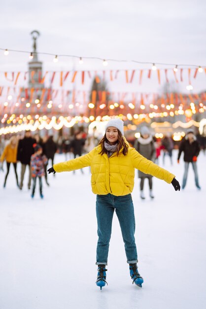 Hermosa mujer se divierte, patinaje sobre hielo activo. Concepto de vacaciones de invierno.