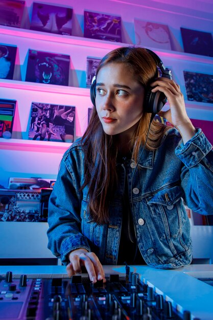 Hermosa mujer Dj alegre disfrutando de escuchar musica por sus auriculares mientras mezcla musica