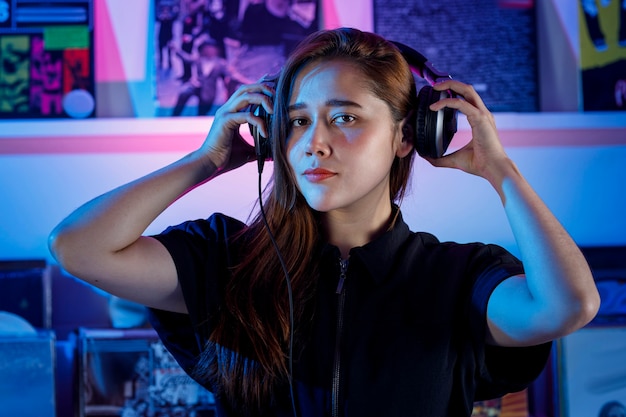 Hermosa mujer Dj alegre disfrutando de escuchar musica por sus auriculares mientras mezcla musica