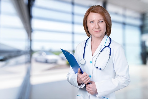 Hermosa mujer doctora sonriente sobre fondo azul del hospital