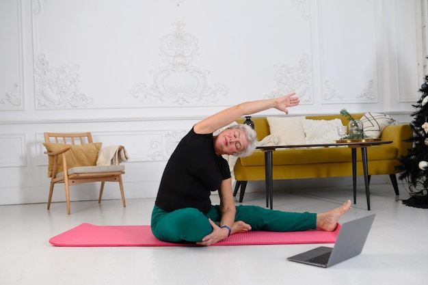 Una hermosa mujer de edad hace yoga en casa en un hermoso interior blanco material de archivo de alta calidad k