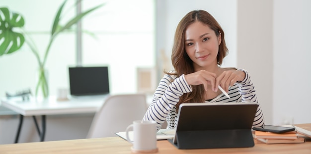 Hermosa mujer editando su proyecto con tableta y sonriendo