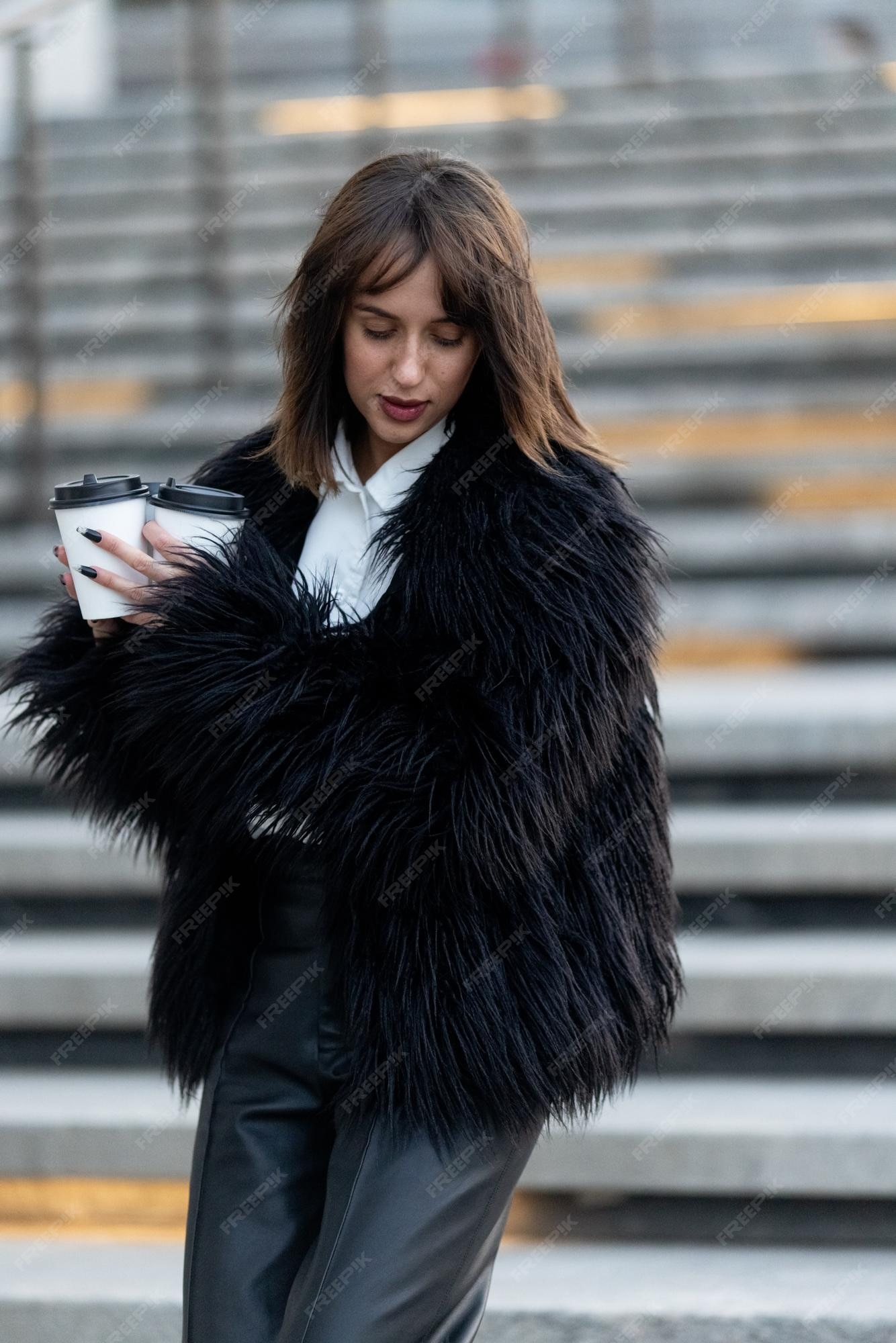 mujer elegante con café para llevar abrigo de piel sintética negro moda a los animales | Foto Premium