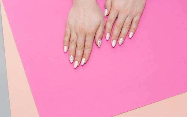 Hermosa mujer elegante manicura sobre un fondo gris con regalo en mano.