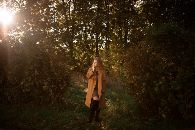 Hermosa mujer elegante de pie en un parque en otoño