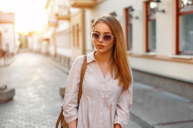 Hermosa mujer elegante en ropa de moda y bolso con gafas de sol