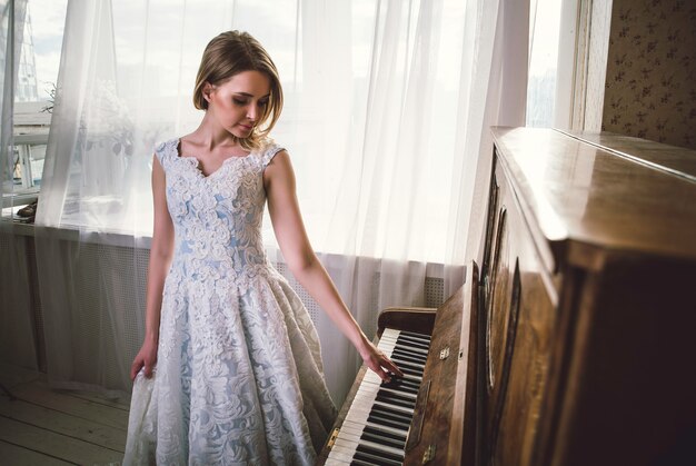 Hermosa mujer con elegante vestido elegante posando en la sala del piano