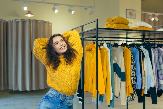 hermosa mujer elige ropa en la tienda cerca del espejo