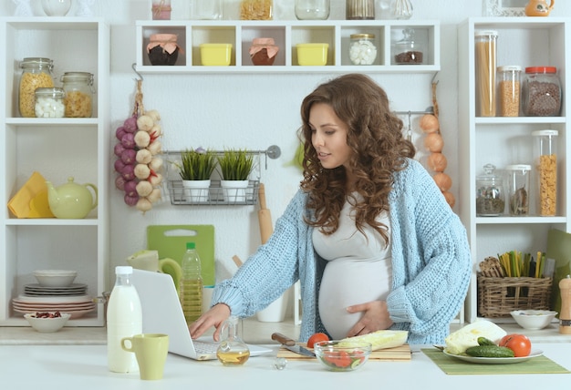 Hermosa mujer embarazada con comida en la cocina