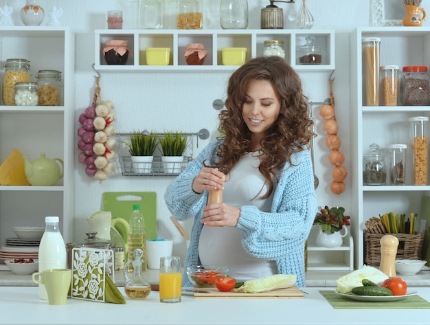 Hermosa mujer embarazada con comida en la cocina