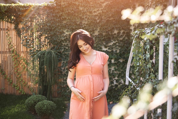 Hermosa mujer embarazada con corona floral al aire libre