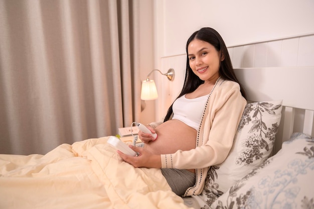 Una hermosa mujer embarazada con un Doppler fetal en el bolsillo para escuchar los latidos del corazón de los bebés en el vientre