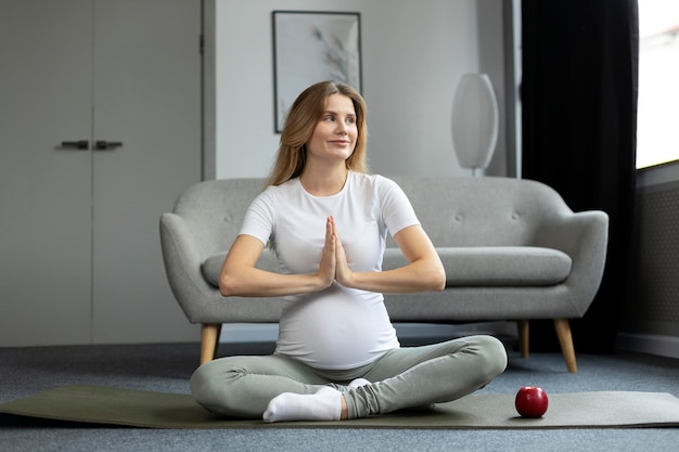 Hermosa mujer embarazada haciendo ejercicio, meditando, haciendo yoga sentada en pose de loto. yoga durante el embarazo
