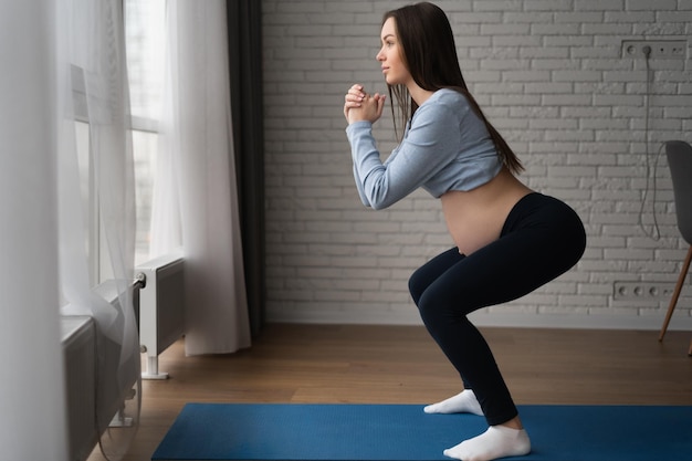 Foto hermosa mujer embarazada haciendo ejercicios en casa