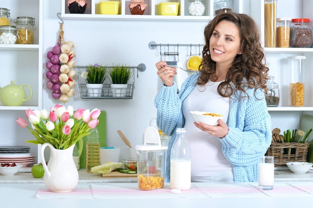 Hermosa mujer embarazada con leche en la cocina