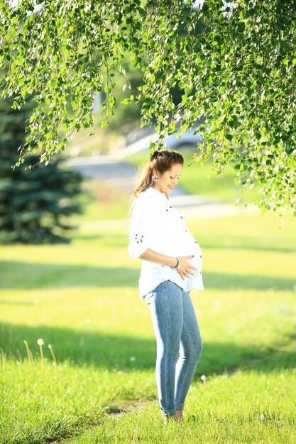 Hermosa mujer embarazada en un paseo por el parque en un día de verano