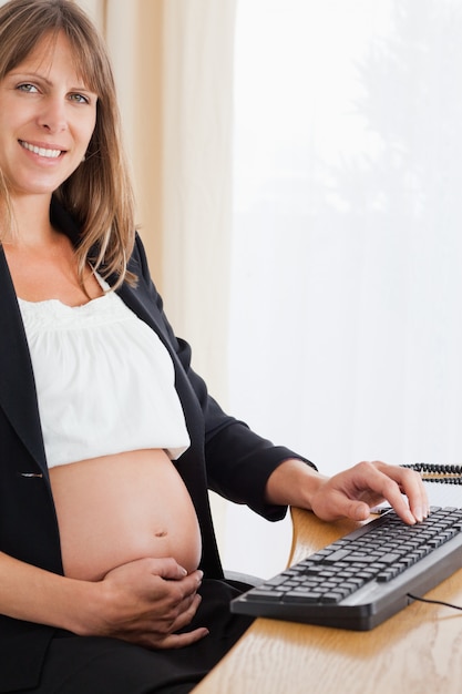 Foto hermosa mujer embarazada que trabaja con una computadora