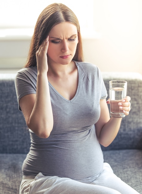 Hermosa mujer embarazada sosteniendo un vaso de agua.