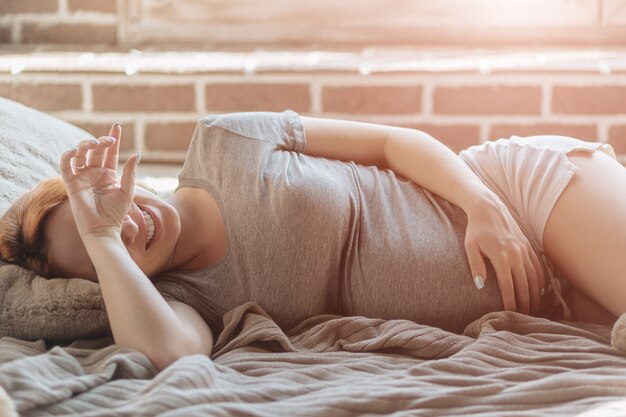 Hermosa mujer embarazada tendida en la cama descansando