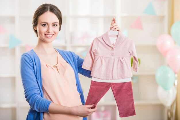 Hermosa mujer embarazada tiene ropa de bebé.