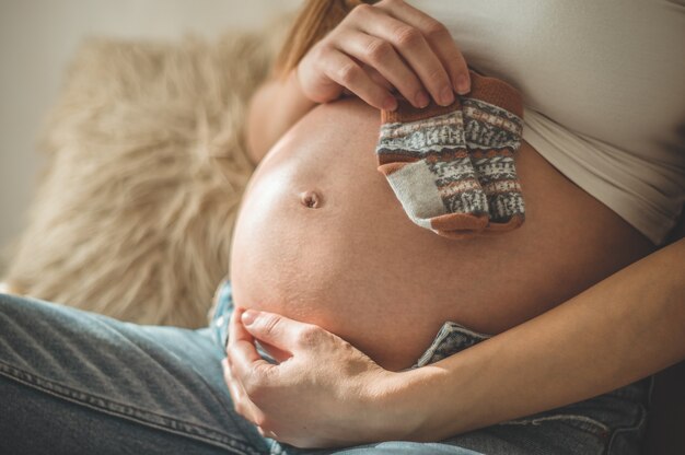 Hermosa mujer embarazada tiene ropa de niño pequeño. Felicidad. Concepto de embarazo