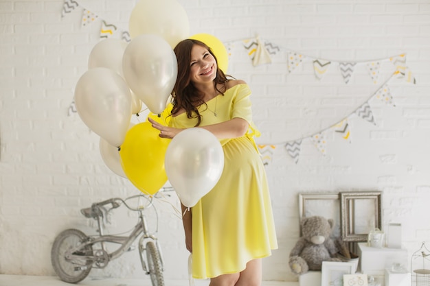 Hermosa mujer embarazada en un vestido amarillo en el estudio