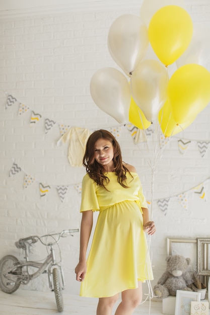 Hermosa mujer embarazada con un vestido amarillo en el estudio