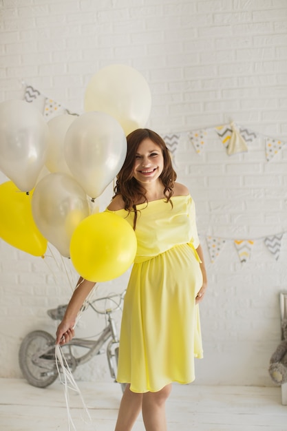 Hermosa mujer embarazada con un vestido amarillo en el estudio.