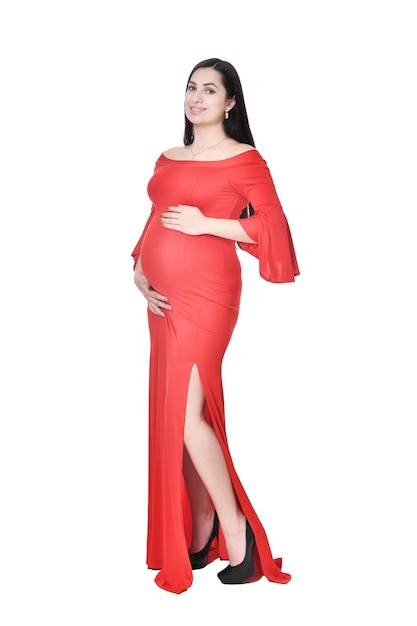 Hermosa mujer embarazada en vestido rojo posando sobre fondo blanco.