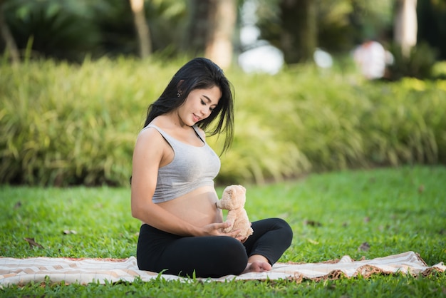 Hermosa mujer embarazada yoga en el parque