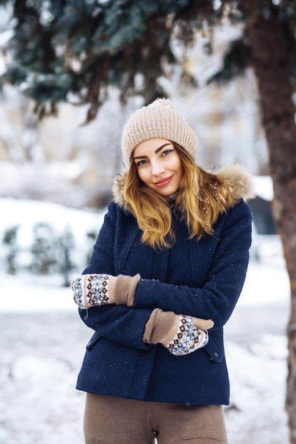 Hermosa mujer se encuentra entre árboles nevados en el bosque de invierno Mujer de moda en el parque de invierno