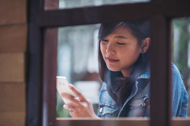 Hermosa mujer escribiendo mensajes de texto en el teléfono inteligente en un café