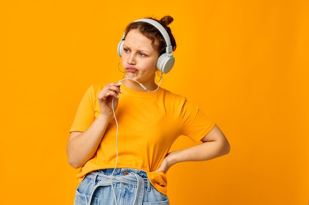Hermosa mujer escuchando música en auriculares estilo juvenil fondo amarillo inalterado