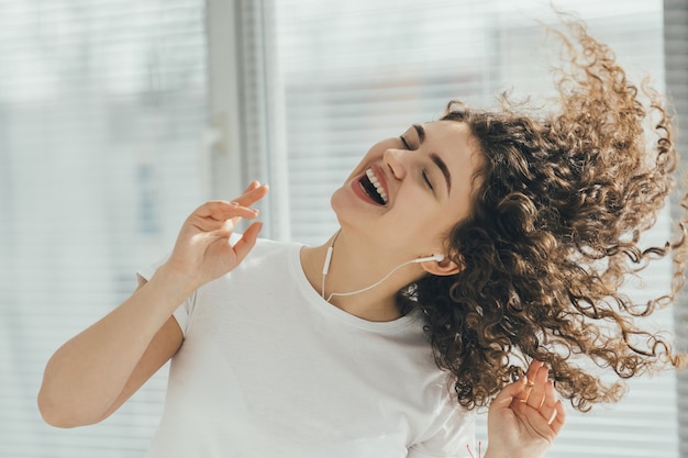 Foto la hermosa mujer escuchando música cerca de la ventana.