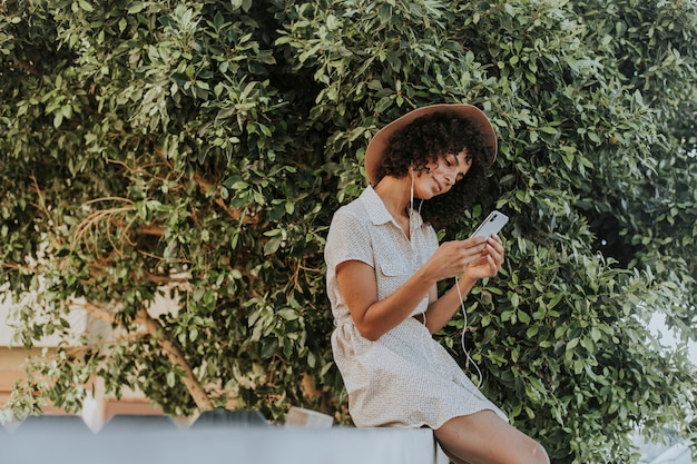 Hermosa mujer escuchando música en un jardín botánico