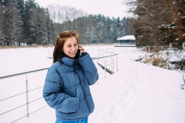 Hermosa mujer esperando tranquilamente hablando por teléfono en un paisaje nevado