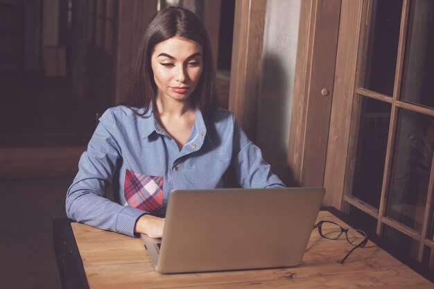 Hermosa mujer está escribiendo en la computadora portátil en la mesa