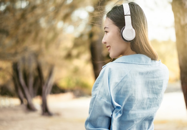 Hermosa mujer está escuchando música en el jardín. Relájese con música de vacaciones.