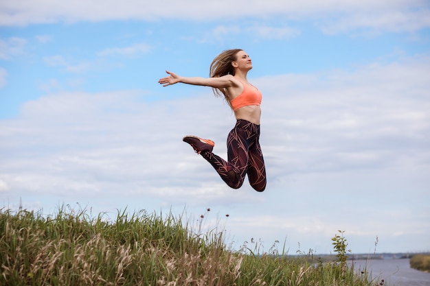 Hermosa mujer está saltando en el aire. La mujer está vestida con ropa deportiva y zapatillas de deporte.