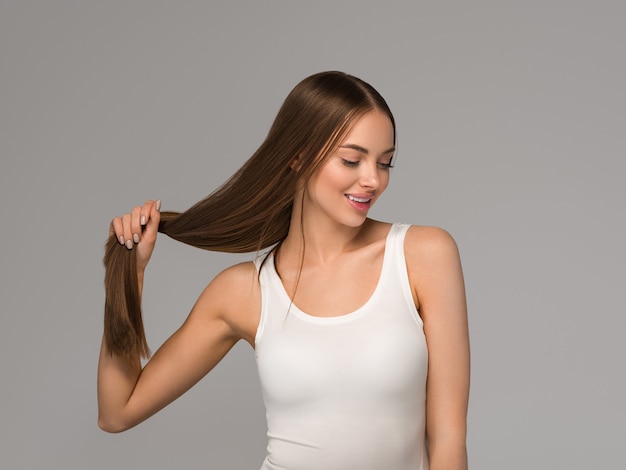 Hermosa mujer con estilo casual de belleza de cola de pelo largo y liso sano. Fondo de color gris