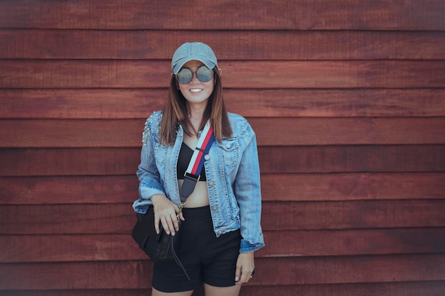 Hermosa mujer de estilo de vida casual con dientes cara sonriente de pie contra la pared de madera