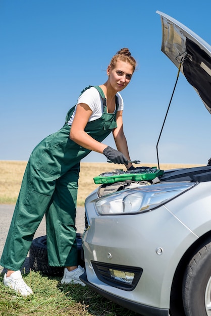 Hermosa mujer europea repara el coche en la carretera