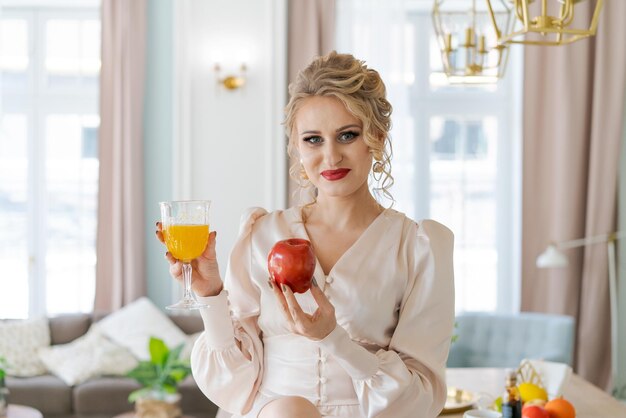 Hermosa mujer exitosa disfrutando de jugo de naranja fresco en su señora de la cocina