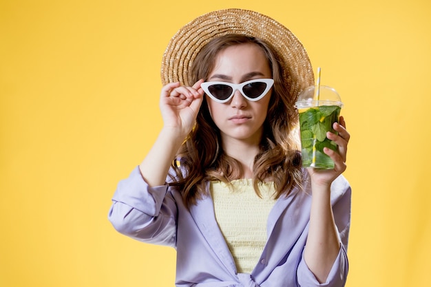 Hermosa mujer expresiva posando con un vaso de bebida