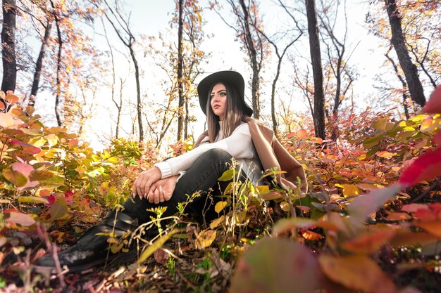 Hermosa mujer feliz con abrigo y sombrero en el bosque