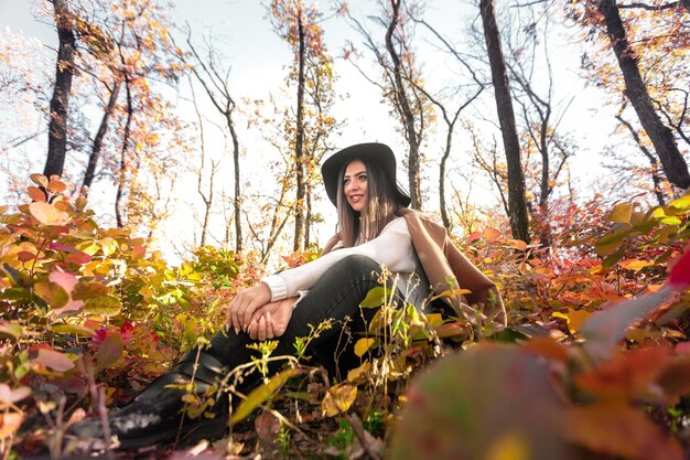 Hermosa mujer feliz con abrigo y sombrero en el bosque