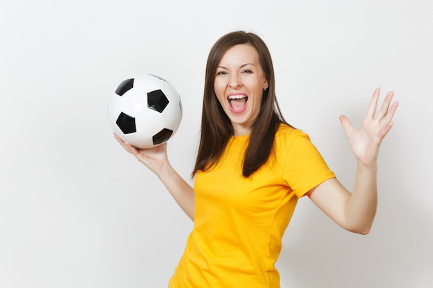 Hermosa mujer feliz alegre joven europea, aficionado al fútbol o jugador en uniforme amarillo con balón de fútbol aislado sobre fondo blanco. Deporte, fútbol, salud, concepto de estilo de vida saludable.