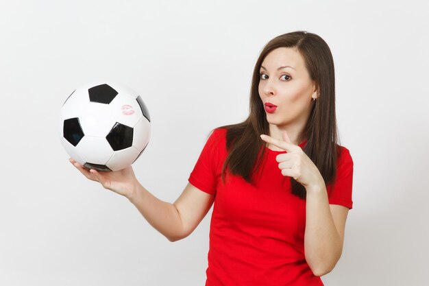 Hermosa mujer feliz alegre joven europea, aficionado al fútbol o jugador en uniforme rojo con balón de fútbol clásico aislado sobre fondo blanco. Deporte, fútbol, salud, concepto de estilo de vida saludable.