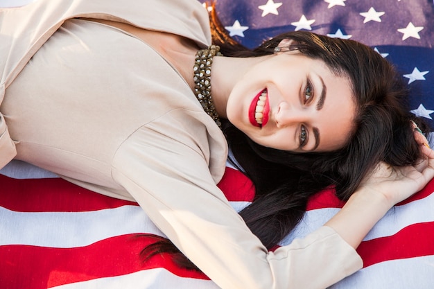 Foto hermosa mujer feliz con bandera estadounidense celebrando el día de la independencia.