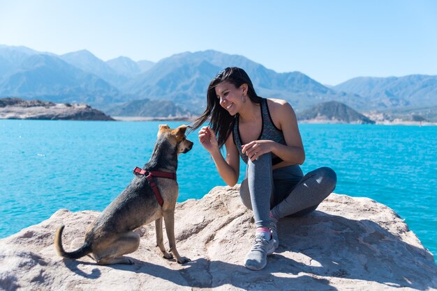 Hermosa mujer feliz en la cima de una montaña con su perro lago entre montañas mujer haciendo ejercicio